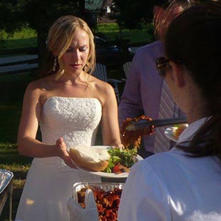 big grill catering server holding a wooden platter of lamb ribs serving wedding guests